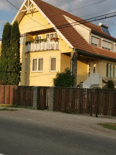 a yellow house with a wooden fence at Sólyom Katalin vendégház in Ujfalù