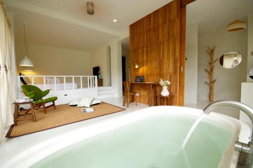 a bathroom with a bath tub and a living room at Proud Phu Fah Maerim Resort in Mae Rim