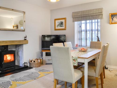 a dining room with a table and a fireplace at The Smithy in New Galloway