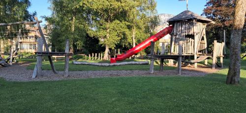 a playground with a red slide in a park at XXL Cosy apartments Villa Goisern, centre with mountain view in Bad Goisern