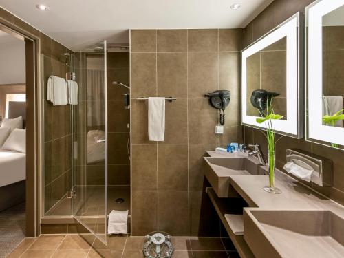a bathroom with two sinks and a shower at Novotel Hannover in Hannover