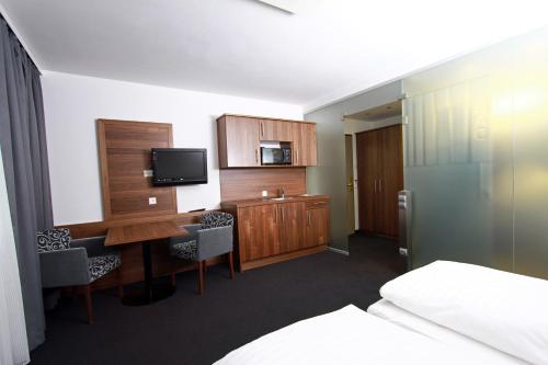 a hotel room with a desk and a tv and a bed at Pension am Kurpark in Vienna