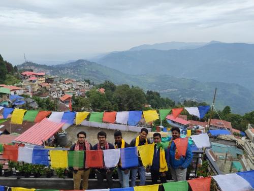 a group of men standing in front of prayer flags at White Sea Homestay in Kurseong