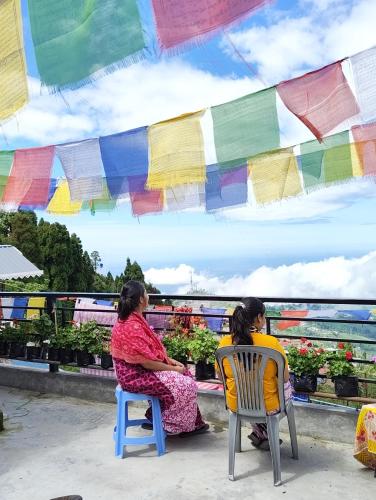 a woman and a child sitting in chairs on a balcony at White Sea Homestay in Kurseong