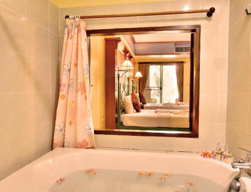 baño con bañera y espejo grande en Pung-Waan Resort & Spa en Kanchanaburi