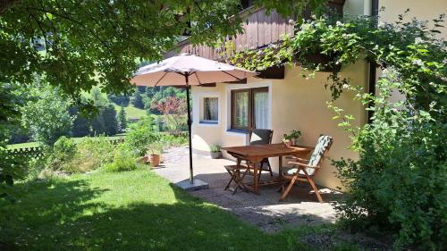 a table and chairs with an umbrella in a garden at Haus Thussn, Ferienwohnung für Familien und Paare in Kirchberg in Tirol
