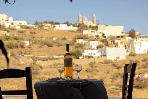 a bottle of wine sitting on a table with two glasses at Mairyren in Ano Syros