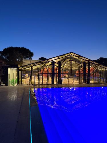 a large glass greenhouse with blue lights next to a pool at Olea Glass Hotel in Tirane