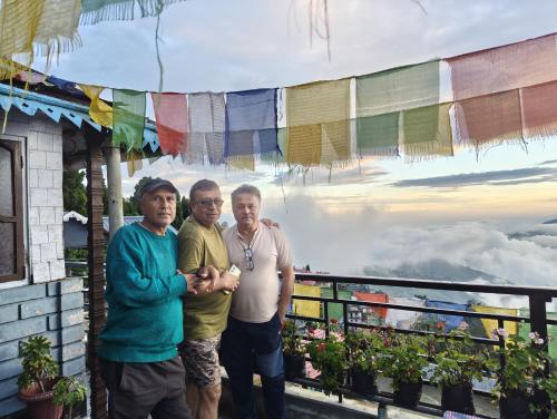 a group of three men standing on a balcony at White Sea Homestay in Kurseong