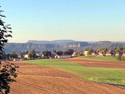 a field with a farm and mountains in the background at Ferienhaus in Sebnitz in Sebnitz