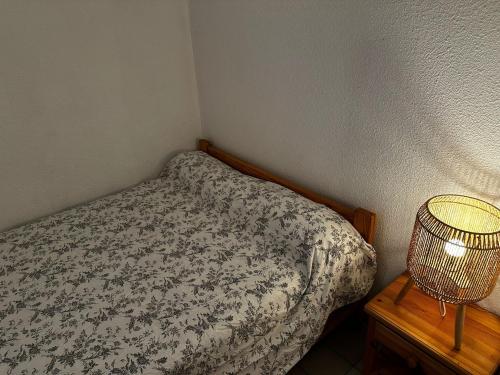 Un dormitorio pequeño con una cama y una lámpara. en Appartement vue sur mer Le Grau du Roi, en Le Grau-du-Roi