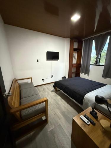 a bedroom with a bed and a couch and a tv at Bunker593 Inn in Tena