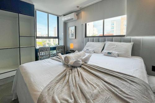 a bedroom with a large white bed with a dress on it at Studio Luxo 150m Praia Intermares 3 Pessoas in Ilha da Restinga