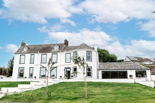 a white house with trees in the yard at Torr House Hotel in Dumfries