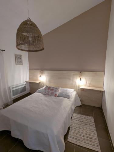 une chambre avec un lit blanc et une lampe suspendue dans l'établissement Petite Maison Chaleureuse avec piscine, à Dolus-d'Oléron