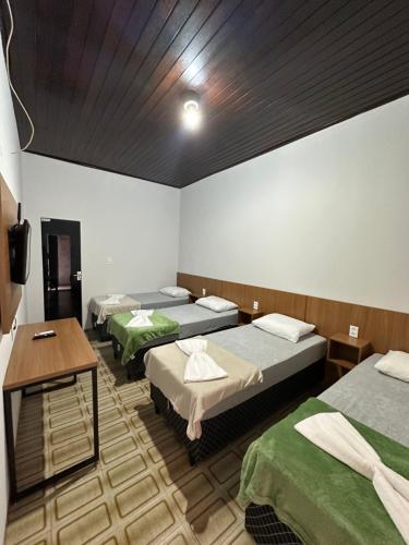 a room with three beds and a table in it at Hotel Manarela in Imperatriz