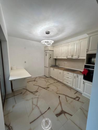 a kitchen with white cabinets and a marble floor at Casa Stefan in Sînmartin