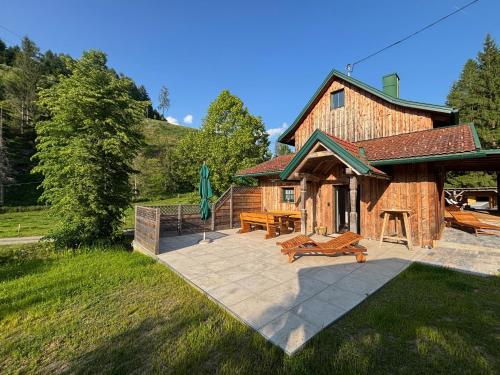 a large wooden building with a patio and picnic tables at Mein Landhaus I Die Bachklanghütte in Sankt Veit in der Gegend