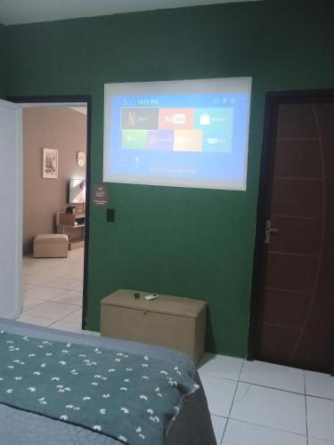 a room with a projection screen on a green wall at Casa MD in Camocim