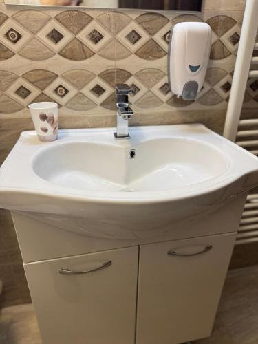 un lavandino da bagno con un dispenser di sapone sopra di Casa DanAdy a Sibiu