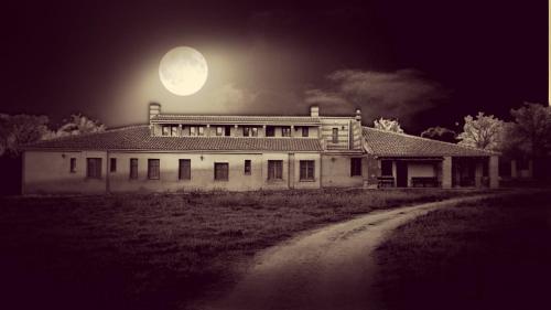 an old house with a full moon in the sky at La Quinta de Melque in San Martín de Montalbán