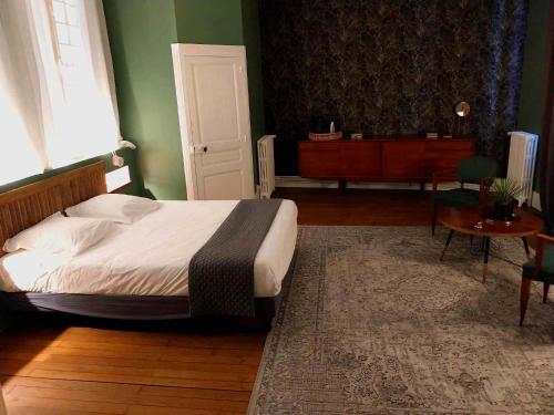 a bedroom with a bed and a table and a door at Maison Tyto Alba in Saint-Victurnien