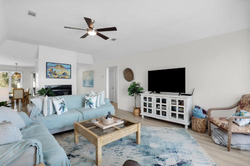 a living room with a blue couch and a tv at Crooked Palm - Marsh Views on Nautical Watch with pool access in Nautical Watch Villas