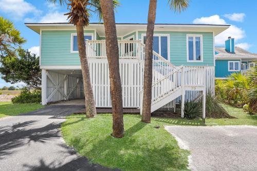 a house with palm trees in front of it at Crooked Palm - Marsh Views on Nautical Watch with pool access in Nautical Watch Villas
