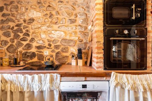 a stone kitchen with a stove and a microwave at Casa Rural El Viejo Almacén, a 20 minutos de Segovia in Losana de Pirón