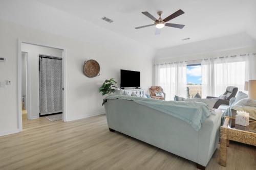 a white living room with a couch and a tv at Crooked Palm - Marsh Views on Nautical Watch with pool access in Nautical Watch Villas