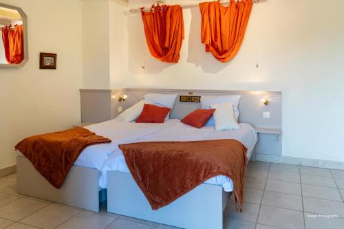 - une chambre avec un grand lit et des rideaux orange dans l'établissement Le duplex du Ried à Muttersholtz en Alsace proche Europa Park, à Muttersholtz