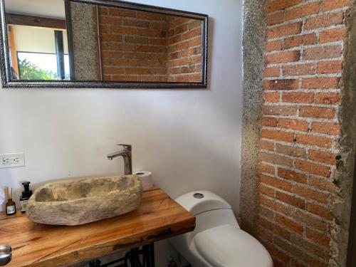 a bathroom with a stone sink and a brick wall at Casa Bambuco Filandia in Filandia