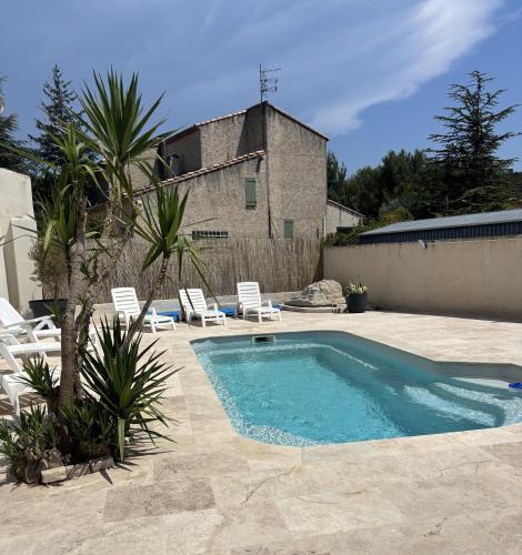 une piscine dans une cour avec des chaises et un bâtiment dans l'établissement Confortable Villa de vacances et sa piscine à Cuges les pins à 2km OK Corral 20km plages, à Cuges-les-Pins