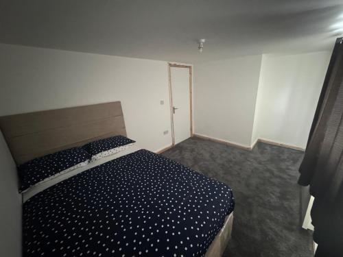 a bedroom with a bed with a black and white comforter at M12 Levenshulme luxury Guesthouse Newly Renovated in Manchester