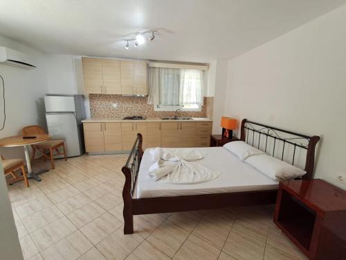 a bedroom with a bed with white sheets and a kitchen at Renting rooms in Himare
