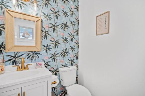 a bathroom with a toilet and a wallpaper with palm trees at Oystershell Cottage in Port Royal