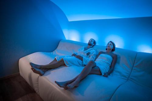 Ein Mann und eine Frau sitzen auf einer Couch mit blauen Lichtern in der Unterkunft Terme Di Venturina in Venturina Terme