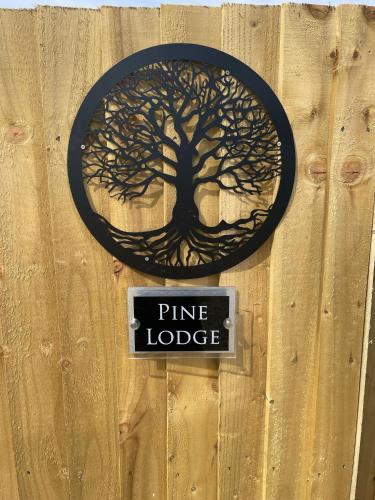 a sign that says pine lodge on a wooden wall at Pine Lodge Posh Glamping With Wood Fired Hot Tub & Big Lincolnshire Skies in Wigtoft