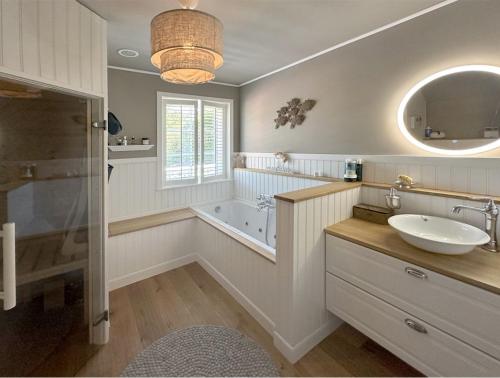 a bathroom with a sink and a tub and a mirror at Das besondere Ferienhaus nähe Nürburgring in Lückenbach