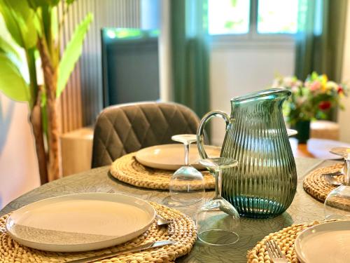 a table with plates and a vase on it at " Souffle Vert " Wifi - TV - 4 personnes in Muret