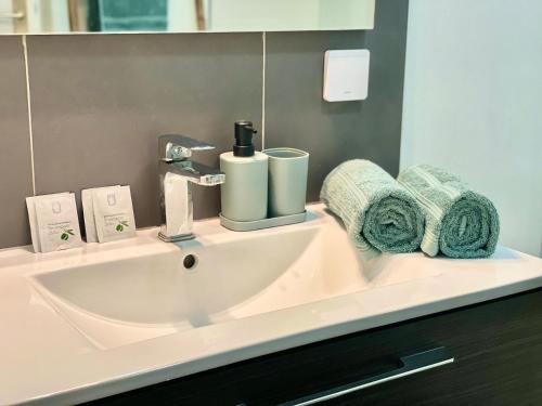 a bathroom with a sink with towels on it at " Souffle Vert " Wifi - TV - 4 personnes in Muret