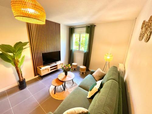 a living room with a green couch and a television at " Souffle Vert " Wifi - TV - 4 personnes in Muret