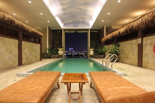 a swimming pool with two benches in a building at Harmoni Suites Hotel in Nagoya