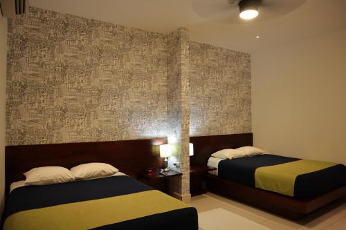 a bedroom with two beds and a wall at Hotel Agualcas in Managua