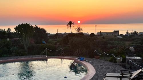 a swimming pool with a sunset in the background at Dammuso Kazen Jezabel in Pantelleria