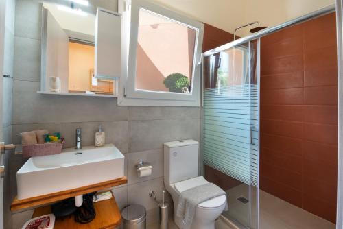 a bathroom with a toilet and a sink and a window at Sueño Central Apartments in Gaios