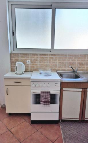 a kitchen with a stove and a sink at Studio Apartmani Šehić in Krvavica
