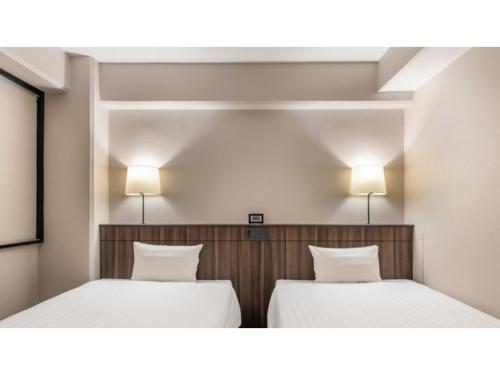 two beds in a room with two lamps on the wall at Sun Hotel Fukuyama - Vacation STAY 53489v in Fukuyama