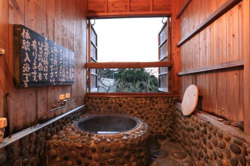Habitación con ventana y baño con bañera de madera. en Sangosho, en Kerizaki