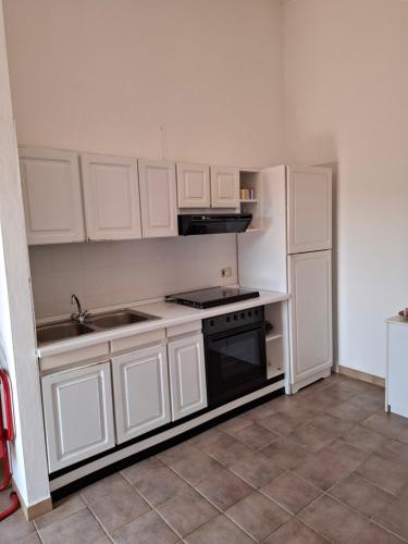 a kitchen with white cabinets and a stove and refrigerator at Casa Giulia in Stintino